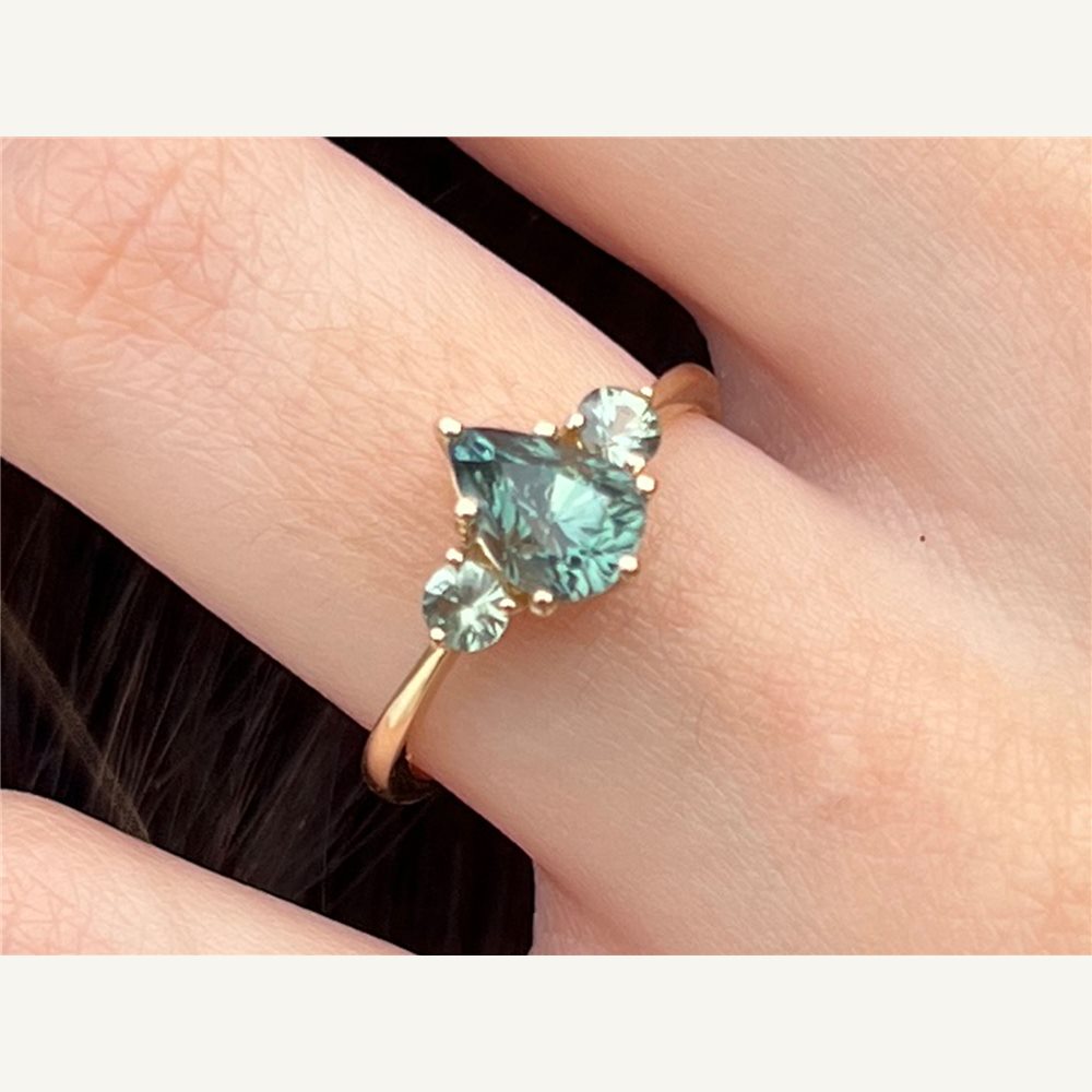 Clarisse teal green pear sapphire trilogy ring worn on hand