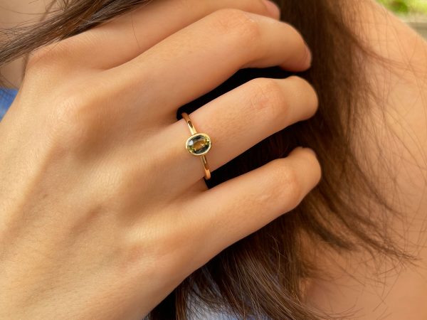 Oval teal petite sapphire gold ring on hand