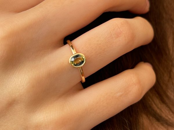 Oval teal petite sapphire gold ring on hand